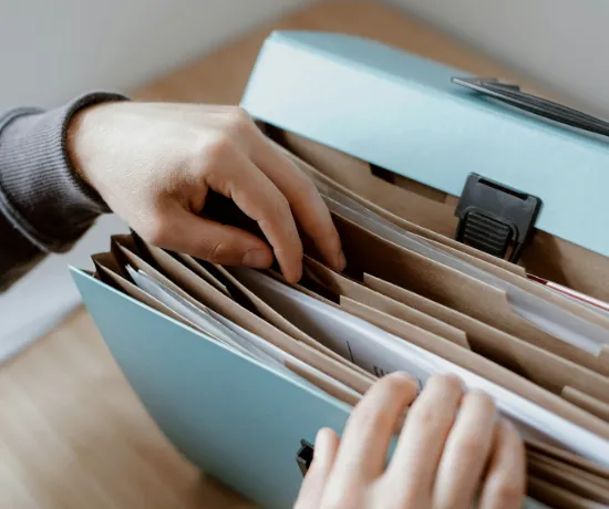 Person organizing student visa documents in a file, representing financial proof, SOP, resume, social media disclosure, and photo requirements for 2025 USA study visa, guided by the best USA student visa consultant in Ahmedabad