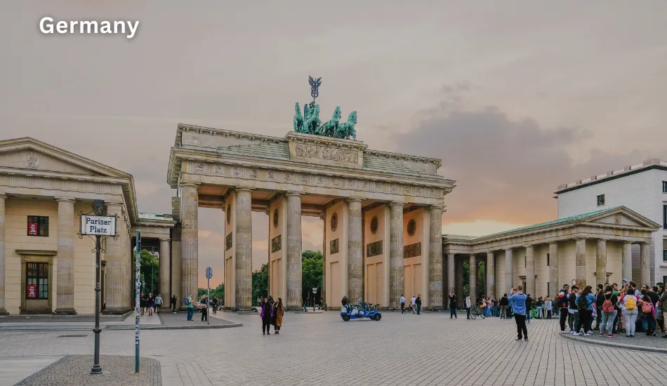 Evening view of the Brandenburg Gate in Berlin with tourists nearby, illustrating Germany as one of the best countries to migrate for affordable education, engineering jobs, and long-term opportunities in the EU.