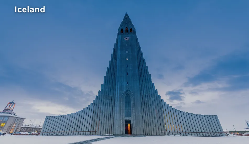Striking front view of Hallgrímskirkja Church in Reykjavik with a snow-covered foreground and overcast sky, representing Iceland as one of the best countries to migrate for safety, sustainability, and a high quality of life in the future.