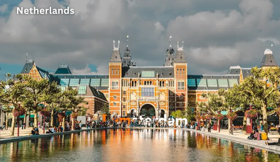 View of the Rijksmuseum with the reflecting pool and “I amsterdam” sign in front, symbolizing the Netherlands as one of the best countries to migrate for English-friendly work culture, strong economy, and quality urban living in Europe.